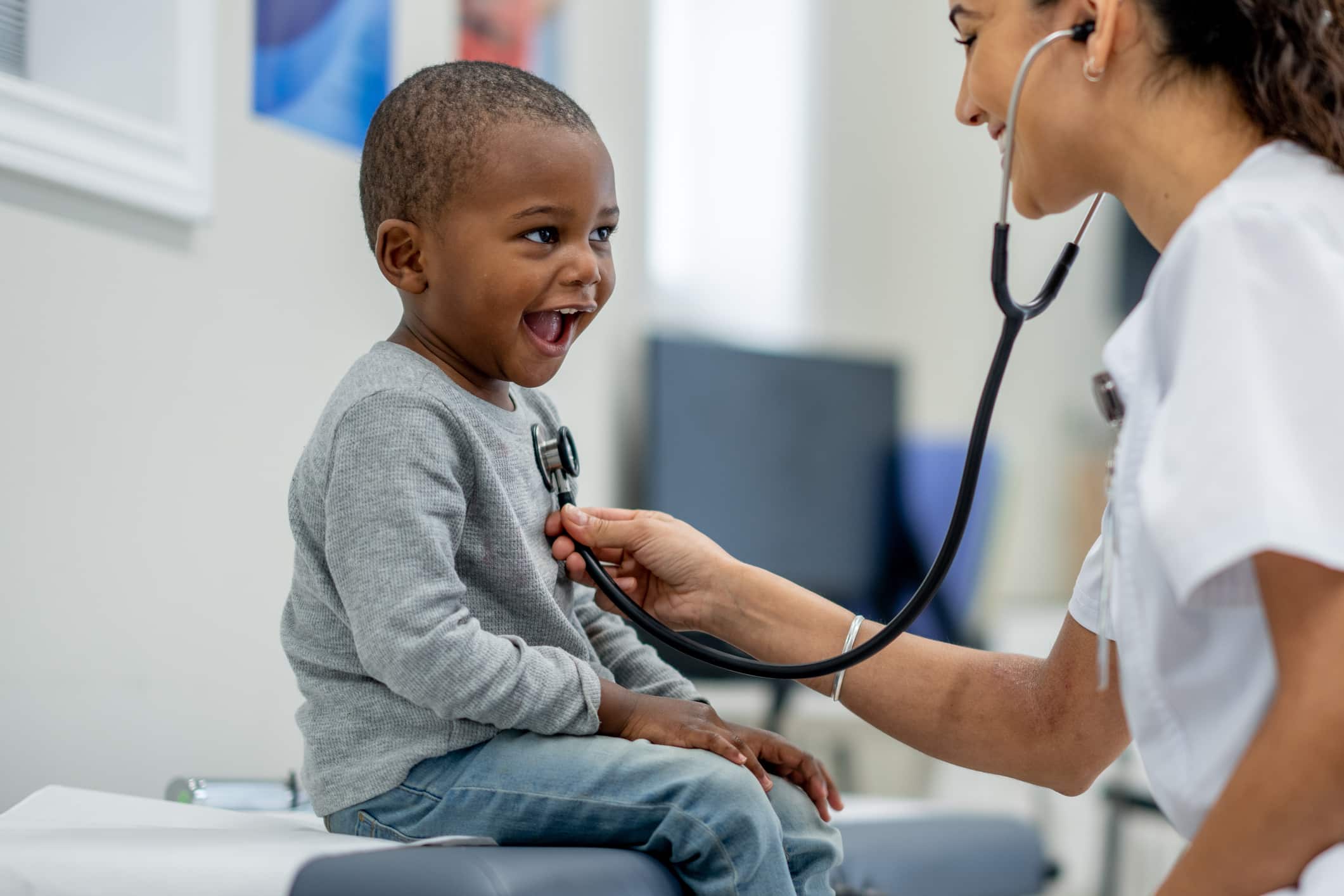 little boy laughing while doctor checks his heart beat